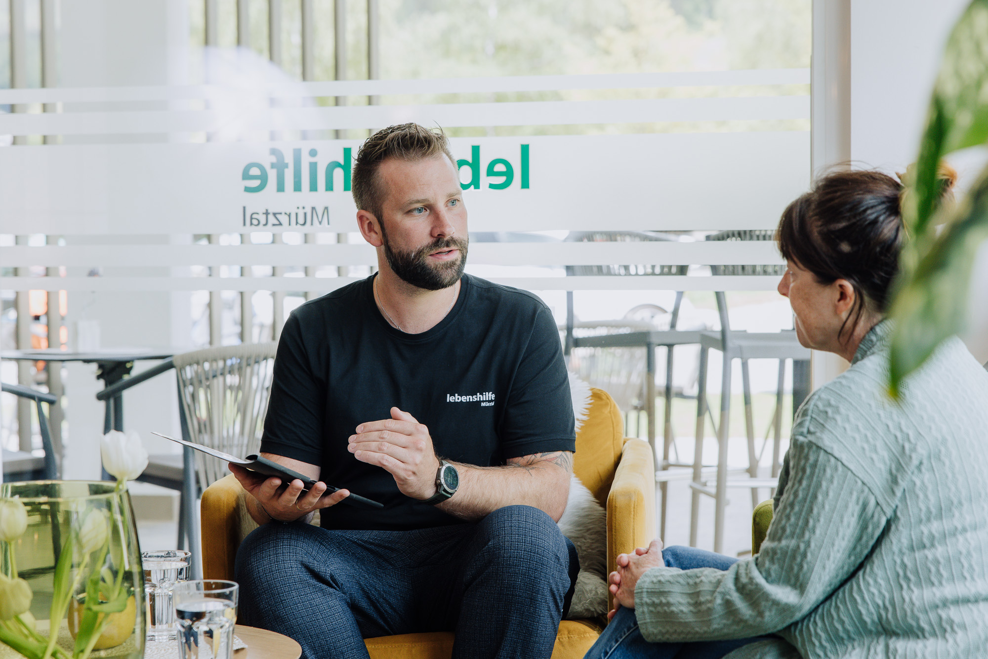 Ein Mann und eine Frau sitzen im hellen Raum und besprechen entspannt.